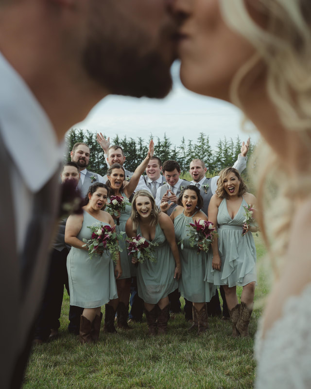 Oregon Wedding Photography, Bridesmaids and groomsmen cheer as bride and groom kiss.